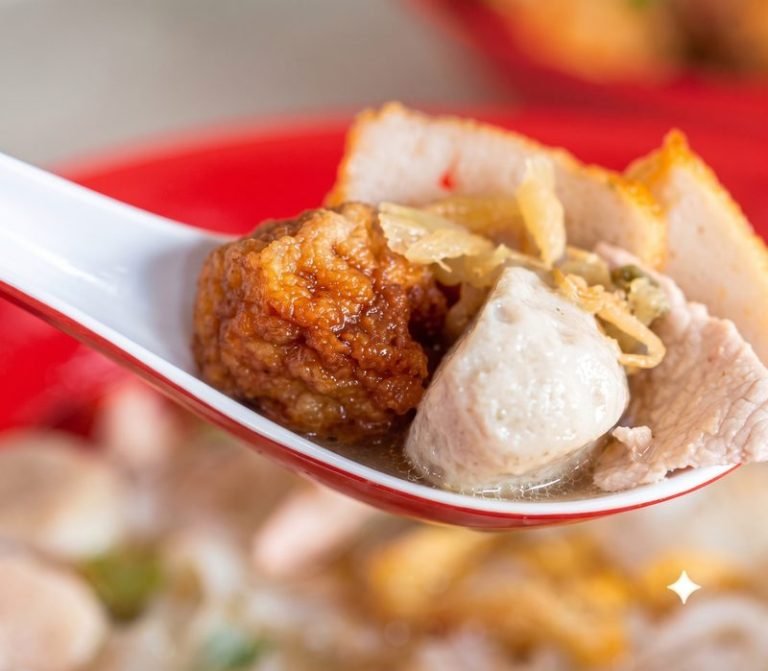 Fishball and pork slices on a spoon over noodle soup